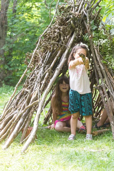 Kids playing next to wooden stick house — Stock Photo, Image