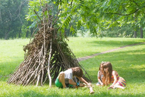 Kids playing next to wooden stick house — Stock Photo, Image