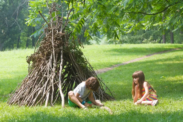 Kids playing next to wooden stick house — Stock Photo, Image