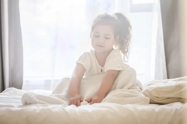 Крытый портрет маленькой девочки, завернутой в одеяло — стоковое фото
