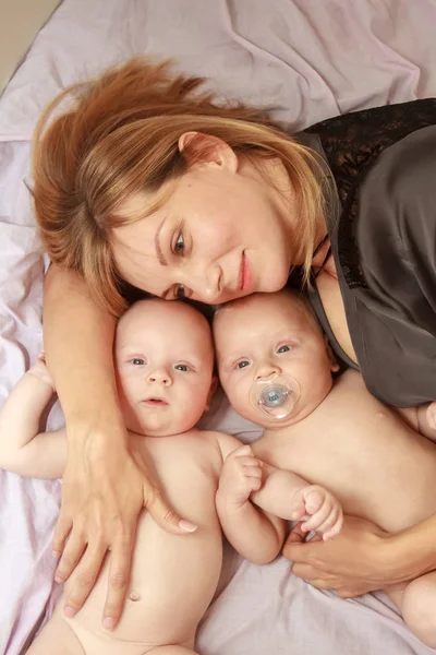Indoor portrait of mother with her twins — Stock Photo, Image