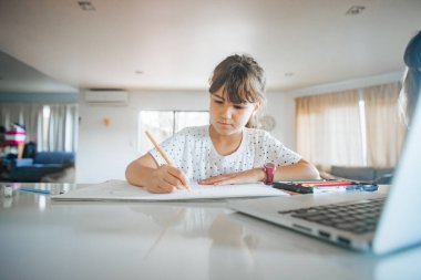 Evde çizim yapan beyaz bir kızın kapalı alanda portresi, evde eğitim, internette öğrenim.