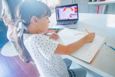 Evde çizim yapan beyaz bir kızın kapalı alanda portresi, evde eğitim, internette öğrenim.