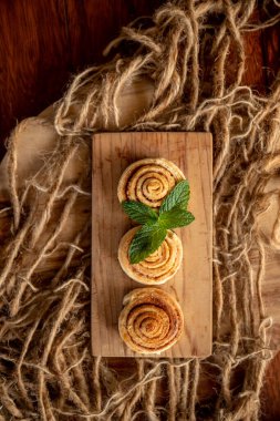 Ahşap zeminde taze pişmiş tarçınlı rulo.