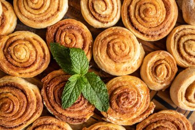 Ahşap zeminde taze pişmiş tarçınlı rulo.