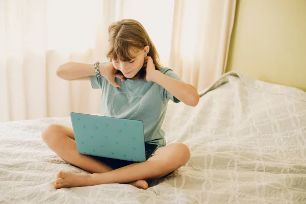 家のベッドの上に寝そべっているラップトップを持つ子供の女の子の屋内カジュアルポートレート — ストック写真