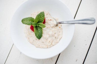 Beyaz ahşap arka planda taze sağlıklı yulaf lapası.