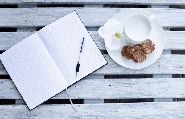 白色木制背景的牛奶 饼干和蓝色笔记本 — 图库照片