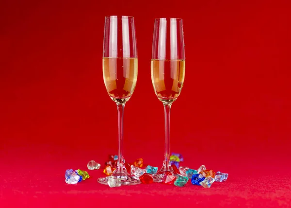 Ποτήρια σαμπάνιας σε κόκκινο φόντο με αφρώδεις κρυστάλλινες πέτρες στη βάση. Πρωτοχρονιά ή ρομαντική γιορτή. Πολυτέλεια. Ελεύθερος χώρος — Φωτογραφία Αρχείου