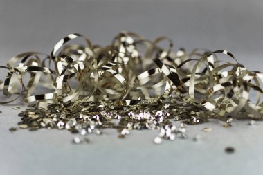 Tarafsız gri arka planda altın pullar ve metalik kurdele. Uzayı kopyala Lüks bir kutlama..