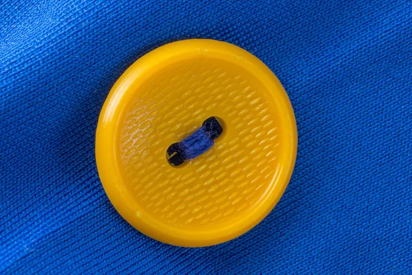 yellow button on blue cloth in macro