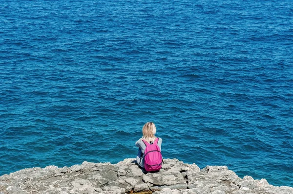 Kvinna turist med ryggsäck avkopplande nära blå havet i Polignano, Apulien, Italien — Stockfoto