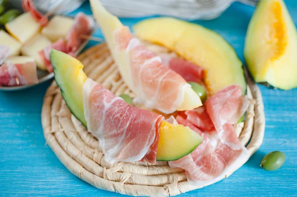 Cantaloupe meloen, sneetjes Italiaanse ham en olijven — Stockfoto