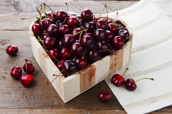 Cherry fresh fruit in a wooden heart shaped bowl — Stock Photo, Image