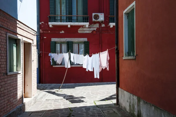 Uma rua com roupas penduradas em Burano, uma pequena ilha perto de Veneza, Itália — Fotografia de Stock