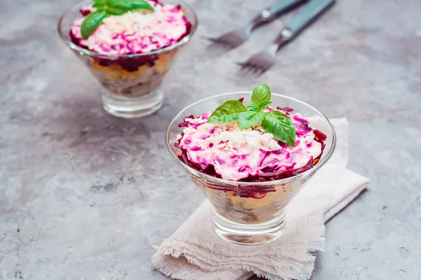 Traditional Russian appetizer of boiled vegetables and fish - a  herring under a fur coat in bowls on the table. Russian salad