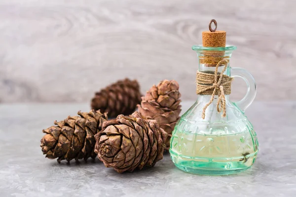 Cedar oil in a bottle and cedar cones on the table. Treatment of resin cedar. Alternative medicine