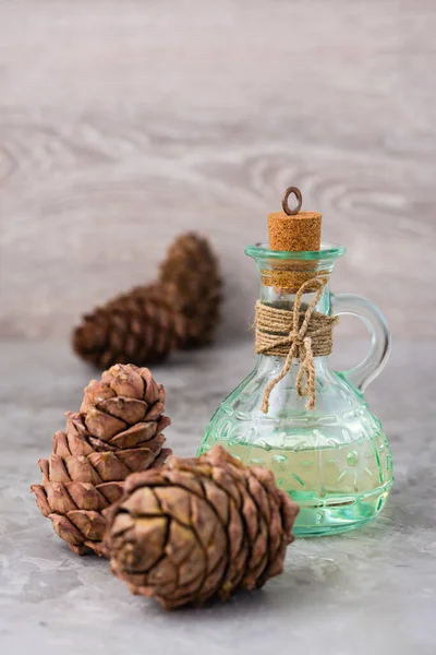Cedar oil in a bottle and cedar cones on the table. Treatment of resin cedar. Alternative medicine, natural medicines