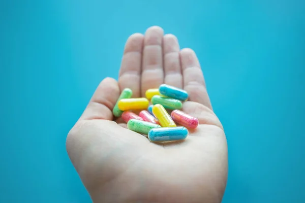 Pastillas Coloridas Medicamentos Mano Femenina Sobre Fondo Azul Diferentes Píldoras — Foto de Stock