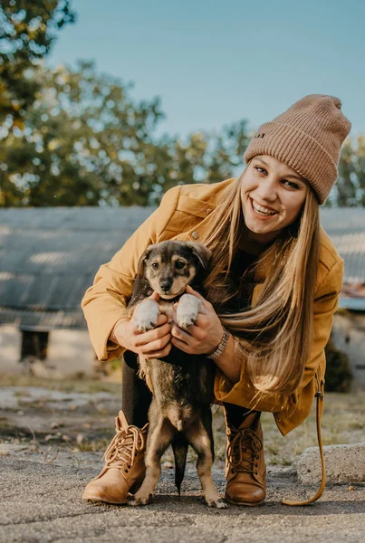 Pet Love. Młoda szczęśliwa kobieta bawi się szczeniakami w jesiennym parku. Autentyczne chwile radości dziewczyna bawiąc się z bezpańskie psy. — Zdjęcie stockowe