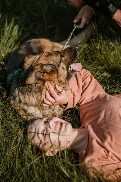 Pet Love. Młoda, bardzo szczęśliwa kobieta bawi się z owczarkiem niemieckim. Autentyczne chwile radosnej dziewczyny bawiącej się psami. Pet love, koncepcja treningu psów — Zdjęcie stockowe