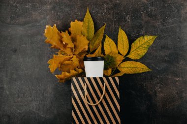 Sonbahar tasarım konsepti, geri dönüştürülmüş kahve fincanı ve sarı yapraklar koyu arka planda. Metin ve logo için boşluk kopyala