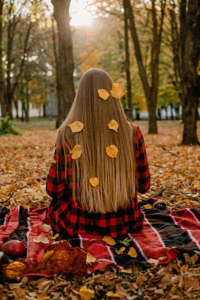 Belo retrato de outono de mulher jovem com cabelo loiro natural longo com folhas amarelas em vestido xadrez vermelho. Menina romântica ao ar livre desfrutando da natureza na luz do sol no pôr do sol — Fotografia de Stock