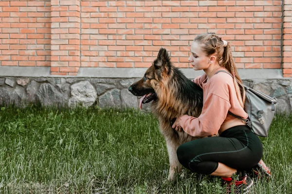 Młoda piękna dziewczyna sportowa z puszystym owczarkiem niemieckim duży pies gra na ulicy miasta. Koncepcja miłości zwierząt domowych — Zdjęcie stockowe