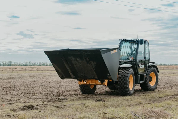 Ковшовый погрузчик JCB, Трактор на демонстрационной площадке агровыставки "АгроЭкспо". Трактор едет по полю. Кропивницкий, Украина 20 апреля 2019 г. . — стоковое фото