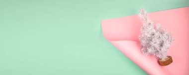 Pembe ve mavi neo-nane arka planında beyaz, yükselen köknar ağacı olan minimalist modern Noel afişi. Minimum şenlikli Noel düzlüğü