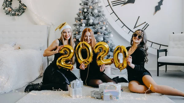 Festa di Capodanno. Festeggiamo il nuovo anno. Tre belle ragazze con palloncini d'oro 2020 festeggiano il nuovo anno. Giovane donna in abito da sera cocktail nero Buon divertimento . — Foto Stock