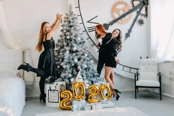 2020年除夕派对。 5.庆祝新年。 三个快乐的年轻女孩，拿着金光闪闪的气球，2020年庆祝新年。 身穿黑色鸡尾酒会晚礼服的年轻女子有乐趣 — 图库照片