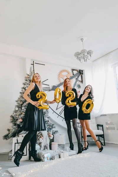 Oudejaarsavond 2020 feest. Vieren van Nieuwjaar. Drie Happy Young meisjes met gouden ballonnen 2020 vieren het nieuwe jaar. Jonge vrouw in zwart cocktail avond jurk Have Fun — Stockfoto