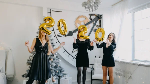 Ragazze felici amici che tengono 2020 palloncini d'oro alla festa di Capodanno, divertirsi insieme. Festa di Capodanno 2020 — Foto Stock