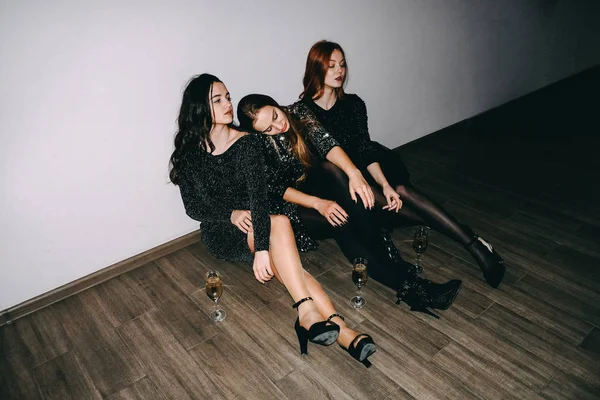 After party, jet set, clubbing, night life concept. Уставшие девушки с бокалами шампанского сидят на полу после празднования вечеринки — стоковое фото