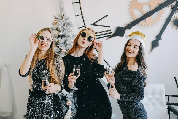 Proost oudejaarsavond, Kerstviering. Drie feestende meisjes die fluiten klappen met champagne. Jonge mooie vrouwen in avondjurk feesten, wijn drinken en dansen — Stockfoto