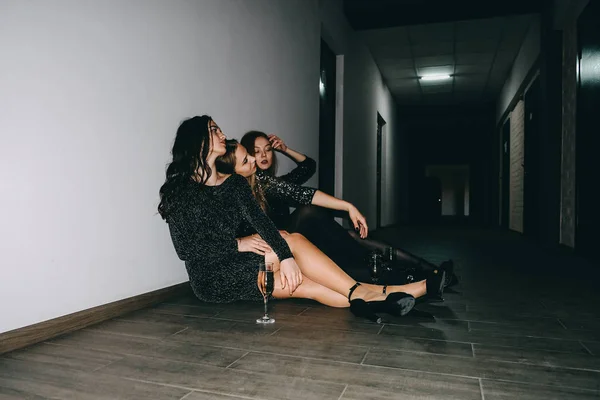 Nochevieja, celebración de cumpleaños. Después de la fiesta, jet set, discotecas, concepto de vida nocturna. Tres hermosas chicas con copas de champán se sientan en el suelo después de celebrar la fiesta —  Fotos de Stock