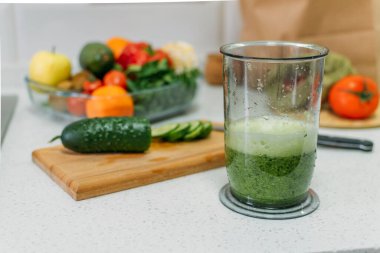Salatalık suyunun faydaları. Yeşil meyve suları detoks ve kilo kaybı için hazırlanıyor. Mutfak masasında bir bardak taze salatalık suyu