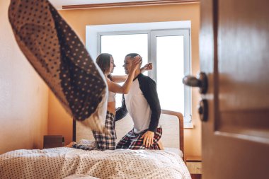 Mutlu genç çift yeni boş bir evde yatakta eğleniyor. Birbirimizin arkadaşlığından keyif alıyoruz. Yastık savaşı. Sevgililer Günü.