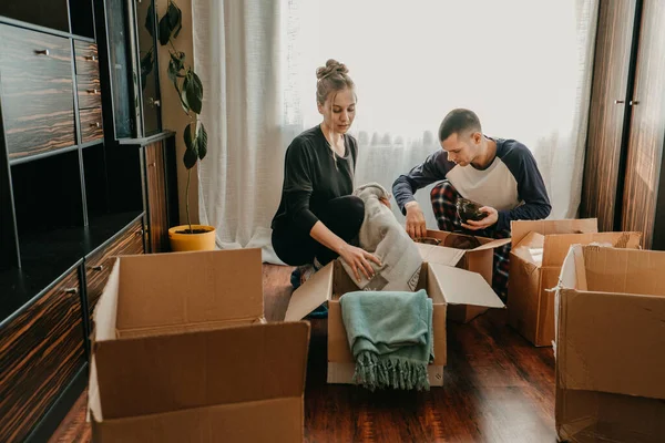 Couple Holding Moving Boxes In New Home. Moving Day, new home, unpacking boxes, newlyweds concept.