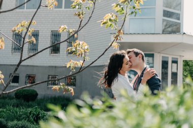 Aşk Çifti konsepti. Birlikte iyi vakit geçirmek, ilişkiyi geliştirmek, fiziksel temas. Mutlu genç adam ve kadın kucaklaşır ve dışarıda öpüşürler.
