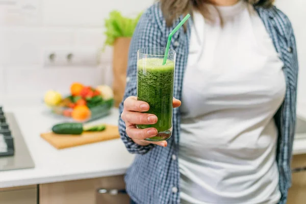 Green Smoothies for Weight Loss. Plus size woman holding in hand glass with slimming Green Smoothie, juice.