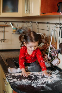 Un Duyusal Oyuncak Bebek için. Bebekler için kolay un duyusal oyun aktivitesi. Sevimli küçük kız mutfak masasında oturur ve unla oynar..