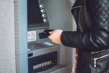 ATM 'den para çekme. Parasını çekmek için ATM kullanan bir kadın. ATM makinesinin yanında kredi kartıyla kadın elinin yakın çekimi.