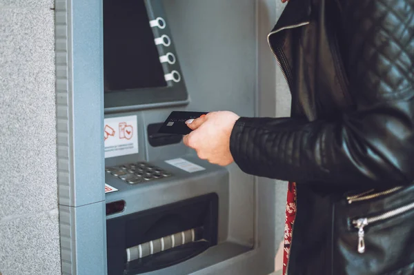 ATM cash withdrawal. Woman using ATM machine to withdraw her money. Close-up of female hand with credit card near ATM machine