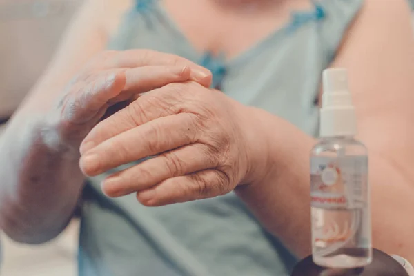 Prevention of Coronavirus Disease COVID-19. Old woman use an alcohol-based hand sanitizer with 60 alcohol, hands close up. How to Prepare for the Coronavirus.