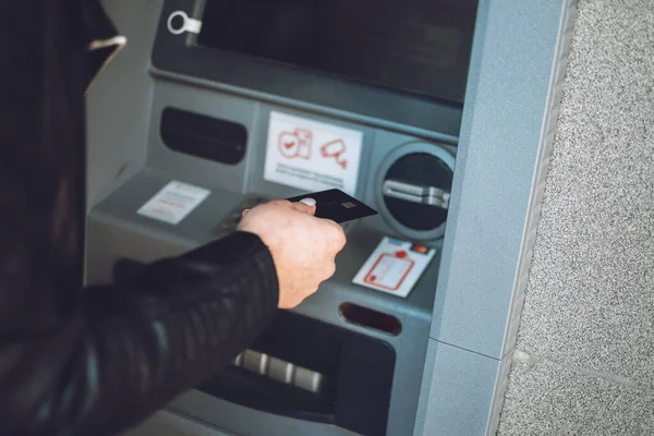 ATM 'den para çekme. Parasını çekmek için ATM kullanan bir kadın. ATM makinesinin yanında kredi kartıyla kadın elinin yakın çekimi.