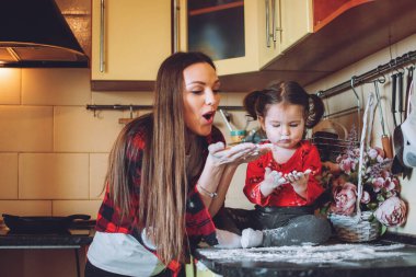 Sosyal Mesafe ve Kendini İzole Etme, Evde Kalma, Karantina, Novel Coronavirus COVID-19 için kendilerini izole eden aileler. Anne ve küçük kızı mutfakta oynuyorlar..