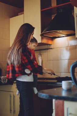 Küçük çocuklarla ev işi. Çocuklar için ev işleri işte. Genç kadın ve kız çocuk küçük yardımcı ev mutfağında eğleniyor. Çocukları meşgul ediyor. Coronavirus Karantinası 'ndaki çocuklar için etkinlikler
