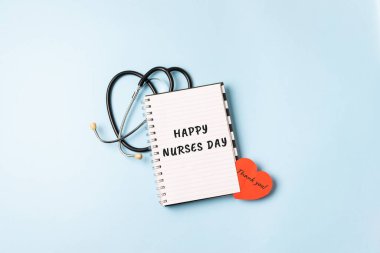 HAPPY NURSES DAY background, banner. International Nurses Day Healthcare and medical concept with notebook, red heart and stethoscope on blue table background clipart